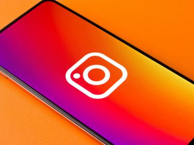 A smartphone with Instagram Reel logo depicted with an orange background