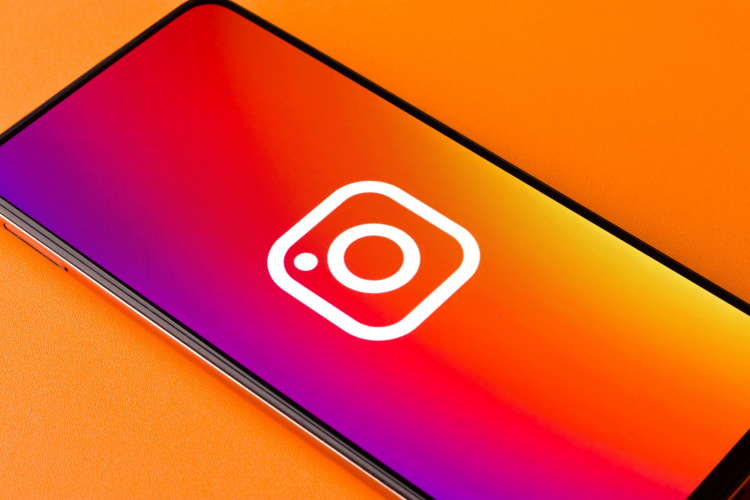 A smartphone with Instagram Reel logo depicted with an orange background