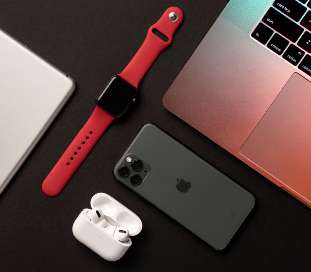 Apple Watch Series 8, AirPods Pro, iPad, MacBook and iPhone 14 Pro Max placed on a dark background