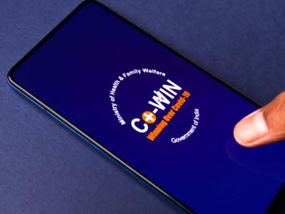 The CoWIN app open on a mobile device, placed on a blue background