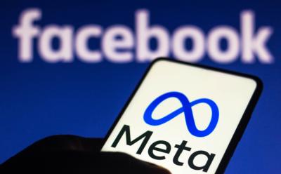 The Meta logo on a smartphone with the Facebook logo in the background