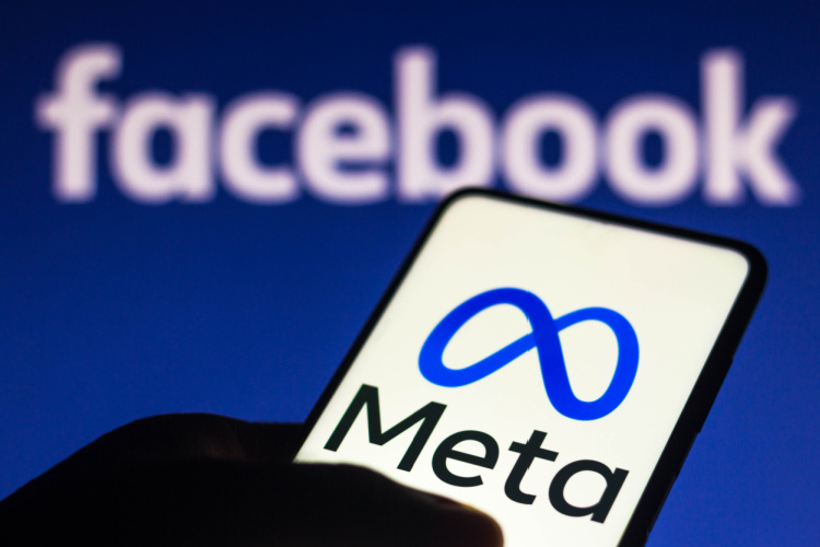 The Meta logo on a smartphone with the Facebook logo in the background