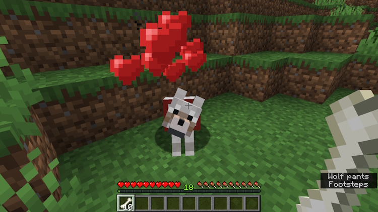 Feeding a wolf some bones and heart particles appearing above it, indicating that you successfully tamed it, making it a dog in Minecraft