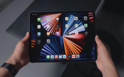 A close up look of hands holding an iPad showing the home screen