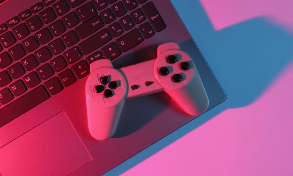 top view of a Gaming controller placed on top of a Laptop in Neon red-blue gradient light