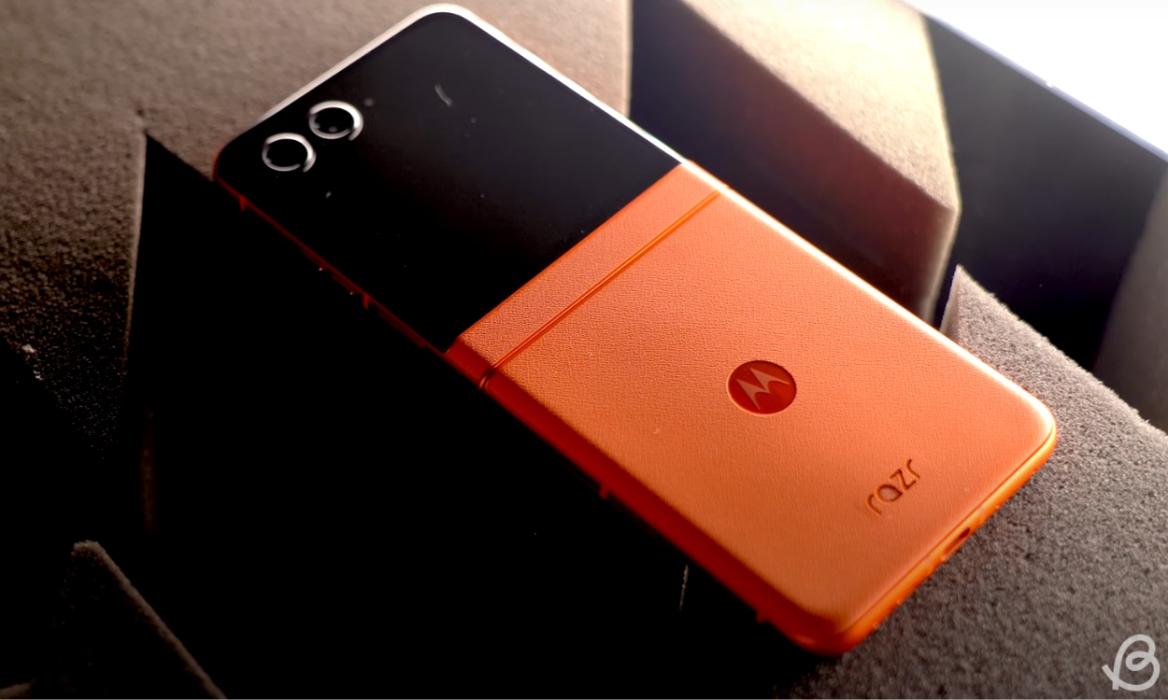 Motorola Razr 50 in Spritz Orange colorway placed with inner display open and facing downwards on a flat surface