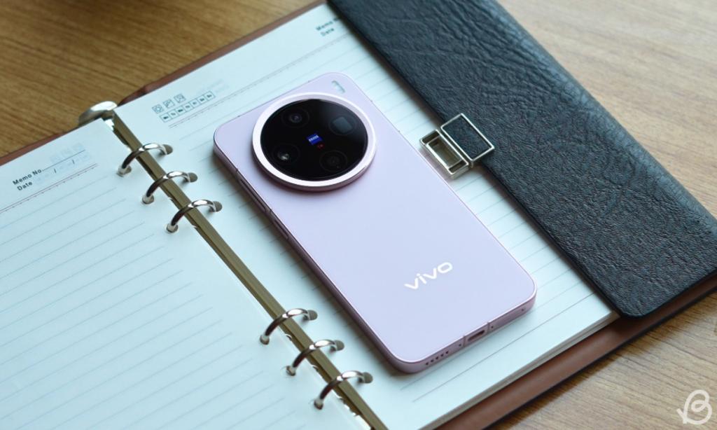 Pink variant of the Vivo X200 Pro Mini placed face down on a notebad