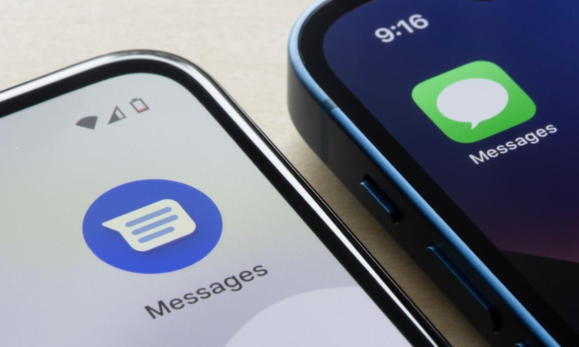 Apple Messages and Google Messages apps on an Android device and iPhone, both placed next to each other on a desk