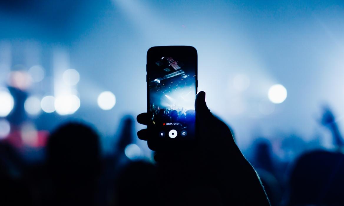 hand holding phone with camera shooting a concert in a low lit environment